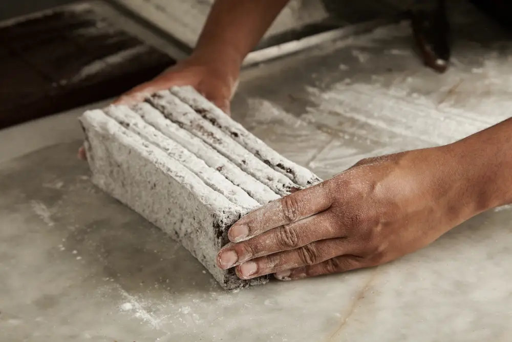 hands black man chef holds freshly baked chocolate bars sugar powder before packing closeup professional artisan confectionery