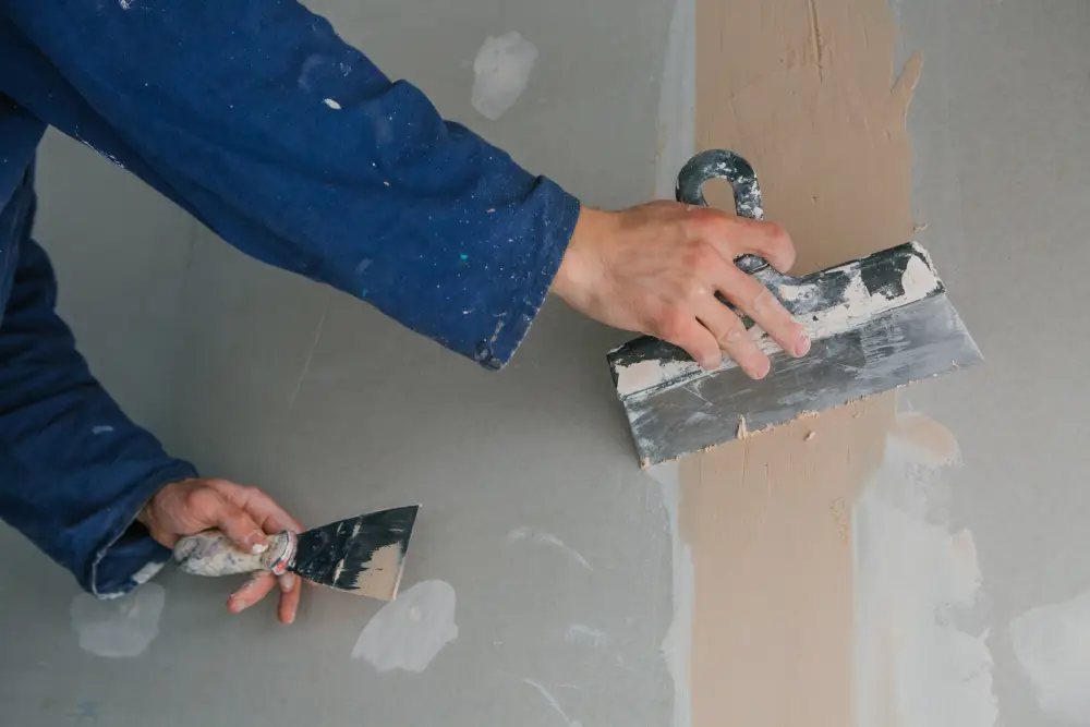 man works plastering two trowels plasterboard blue uniform